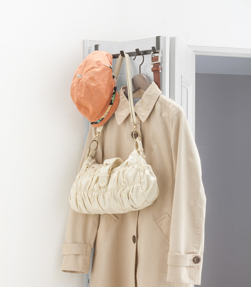 View 9 - Black Over-the-Door Hanger holding purse, hat, belt and jacket on closet door by Yamazaki Home.