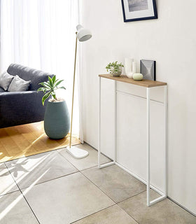 Yamazaki Home Narrow Entryway Console Table holing a small plant next to a floor lamp.  view 4