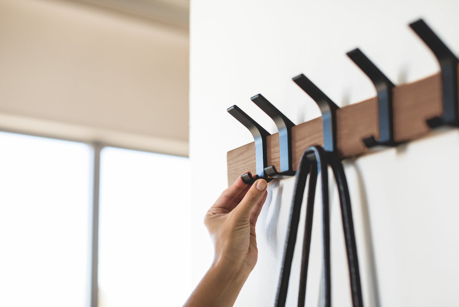 View 10 - Close up view of walnut Wall-Mounted Coat Hanger hooks holding bag by Yamazaki Home.