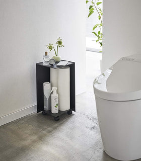 Black Rolling Bathroom Organizer holding toilet paper and supplies in bathroom by Yamazaki Home. view 9