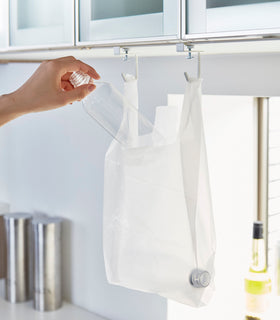 White kitchen Undershelf Hangers holding recycling bag by Yamazaki Home. view 6