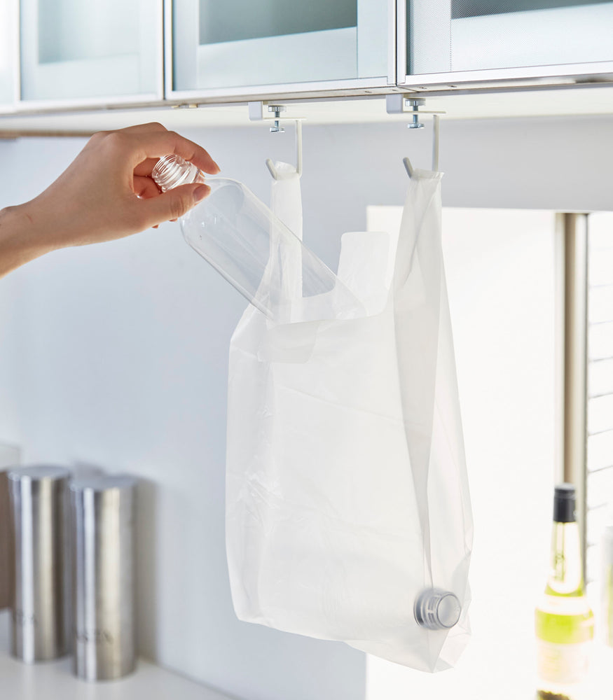 View 6 - White kitchen Undershelf Hangers holding recycling bag by Yamazaki Home.