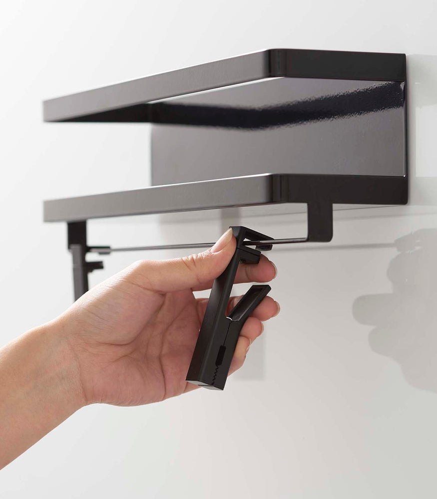 View 13 - Person attatching clips to black Magnetic Organizer with Easy-Grip Rotating Clips by Yamazaki Home.