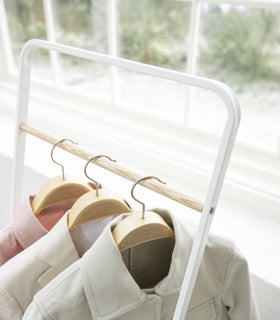 Close up top view of white Clothes Rack holding jackets by Yamazaki Home. view 3