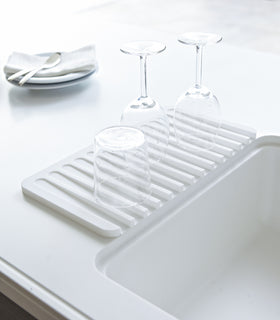 White Dish Drainer Tray holding cups on countertop by Yamazaki Home. view 2