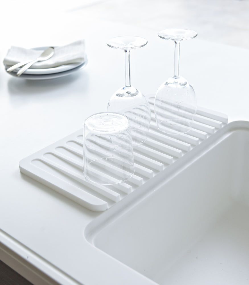 View 2 - White Dish Drainer Tray holding cups on countertop by Yamazaki Home.