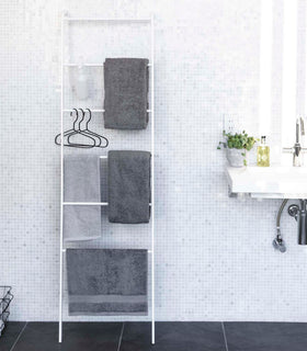 Front view of white Leaning Ladder Rack holding towels in bathroom by Yamazaki Home. view 2