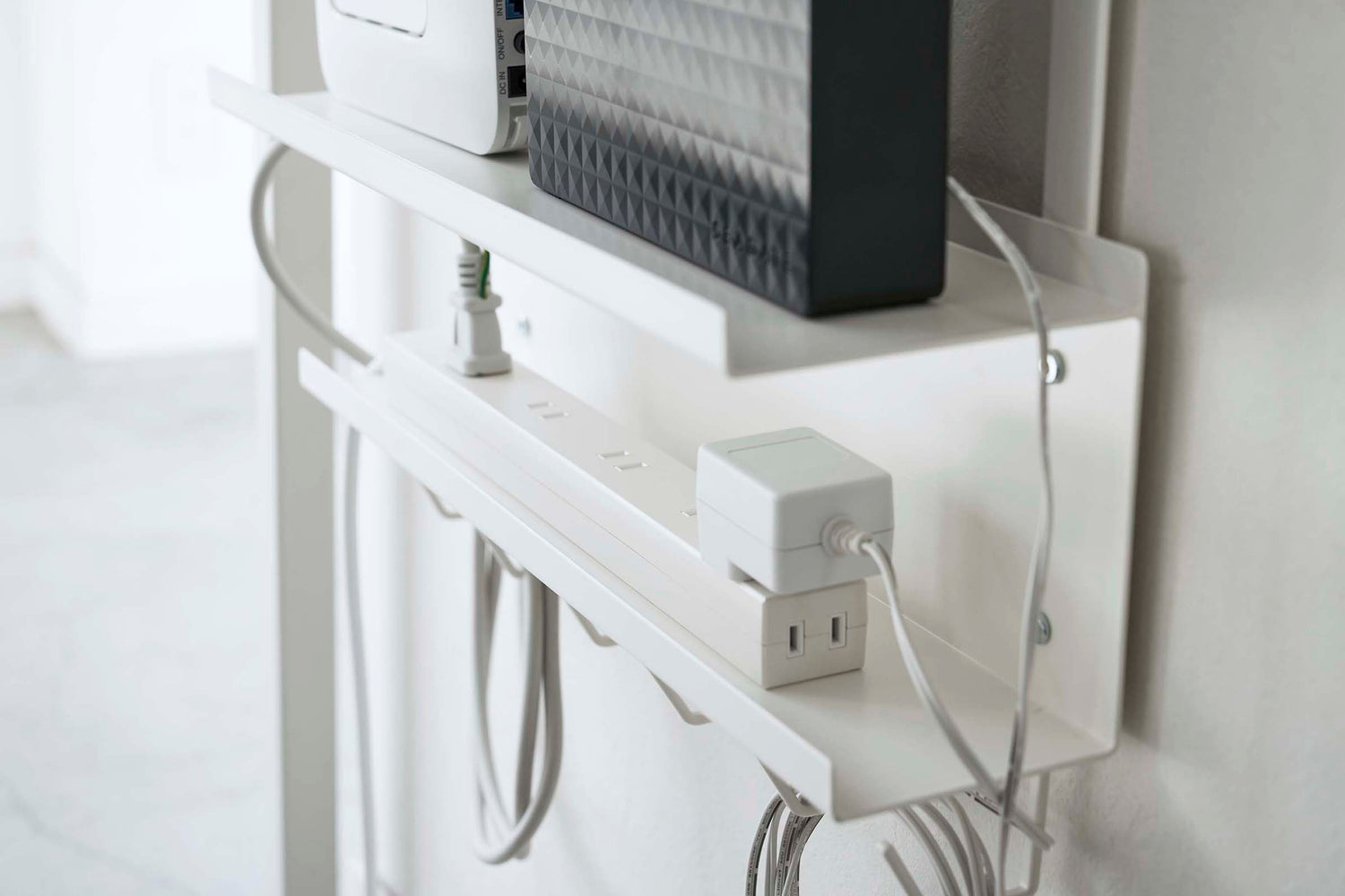View 4 - Close up view of white Wall-Mount Cable and Router Storage Rack power cord by Yamazaki Home.