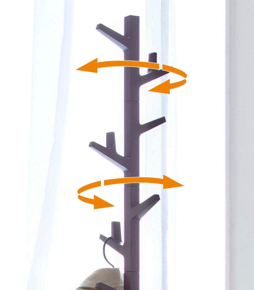 View 10 - Yamazaki's Brown coat rack in the shape of a tree marked with orange arrows to indicate its mobility.