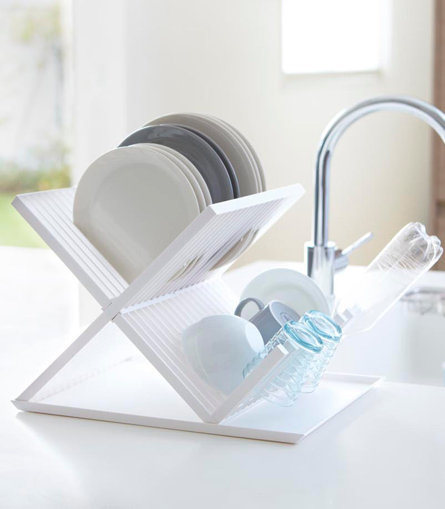 View 3 - Side view of white X-Shaped Dish Rack holding dinnerware by Yamazaki Home.