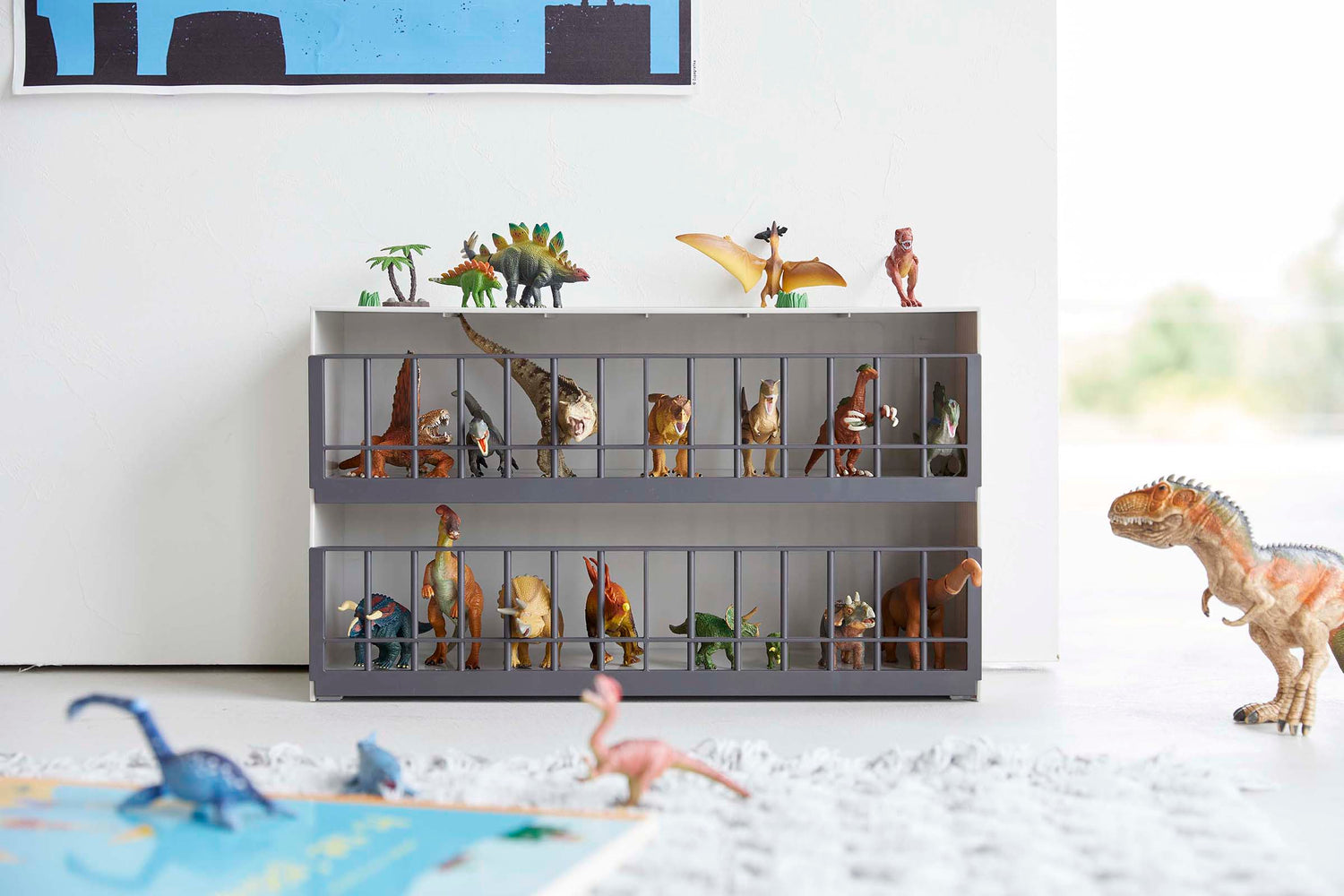 View 4 - Front view of white Two-Tier Toy Dinosaur and Animal Storage Rack in living room play area holding toy dinosaurs by Yamazaki Home.