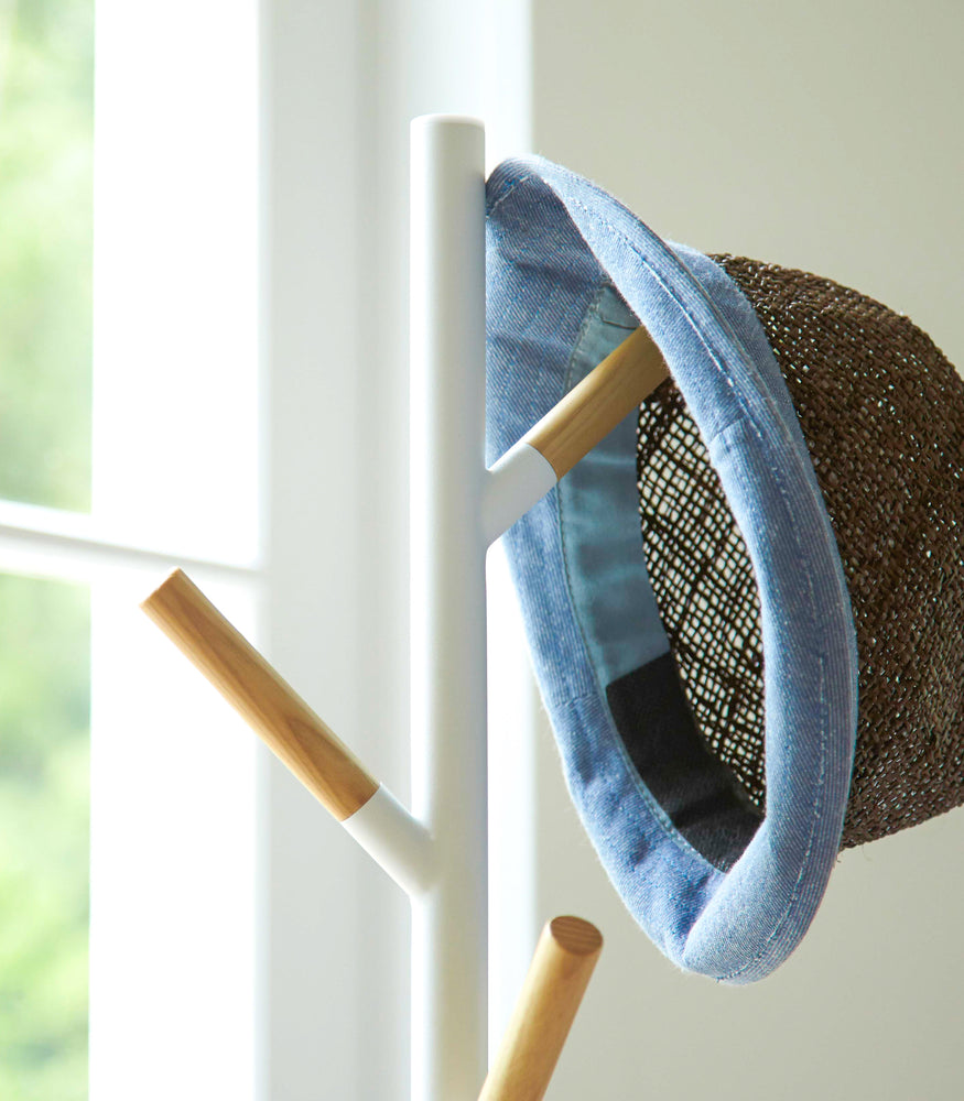 View 3 - Close up top view of white Freestanding Coat Rack displaying hat by Yamazaki Home.