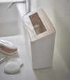 Side view of White Countertop Waste Bin on bathroom sink countertop by Yamazaki Home.