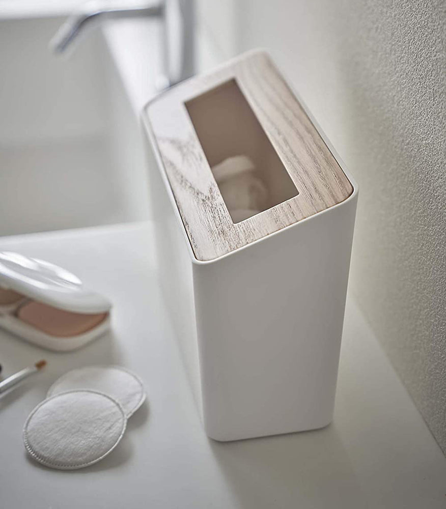 View 4 - Side view of White Countertop Waste Bin on bathroom sink countertop by Yamazaki Home.