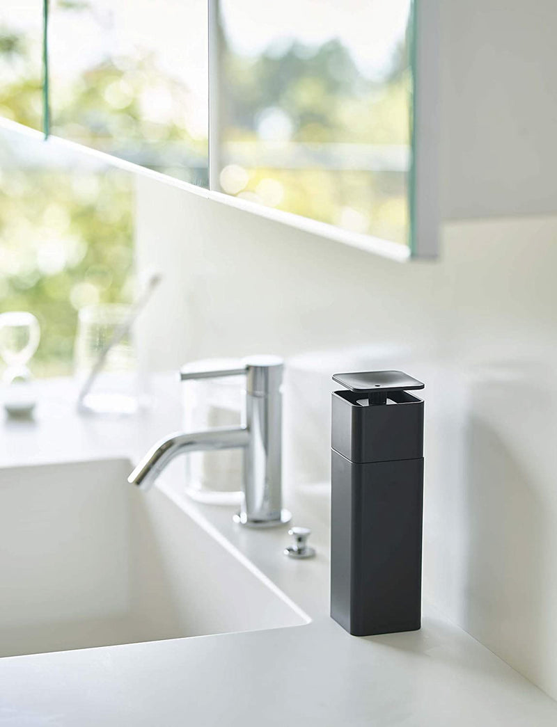 Black One-Handed Push Soap Dispenser on bathroom sink countertop by Yamazaki Home.