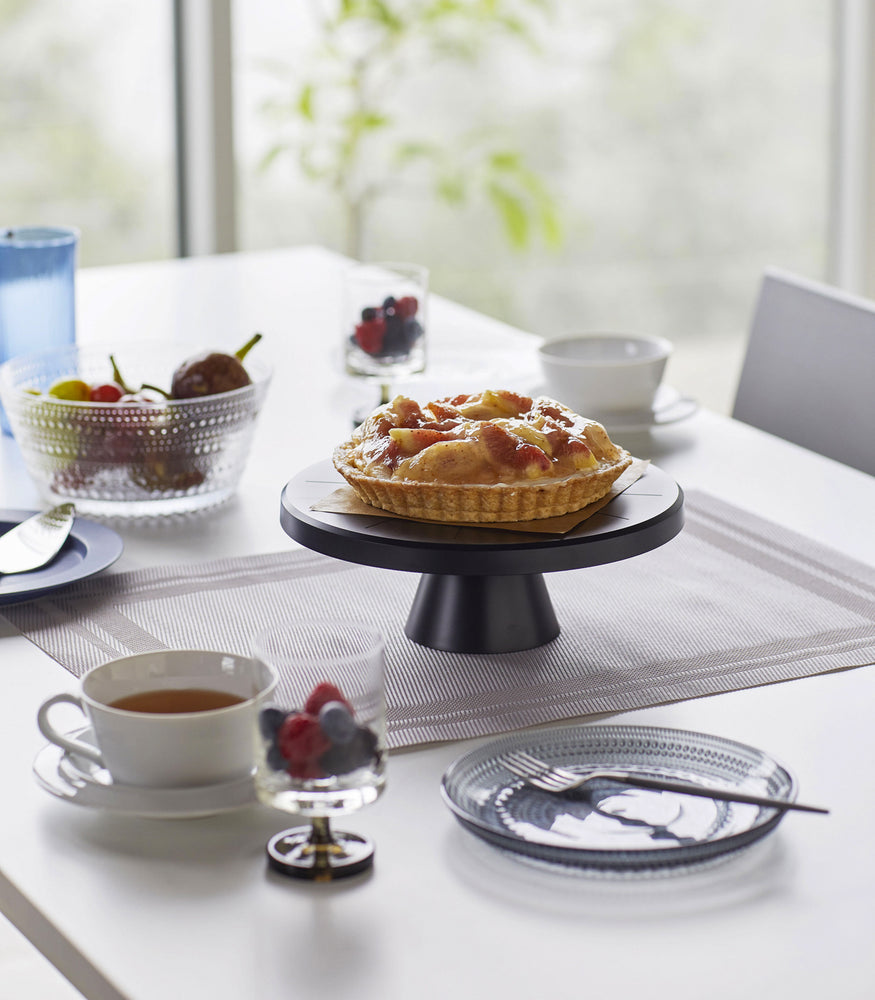 View 10 - Black Stackable Serving Stand displaying a pie on a dining room table by Yamazaki Home.