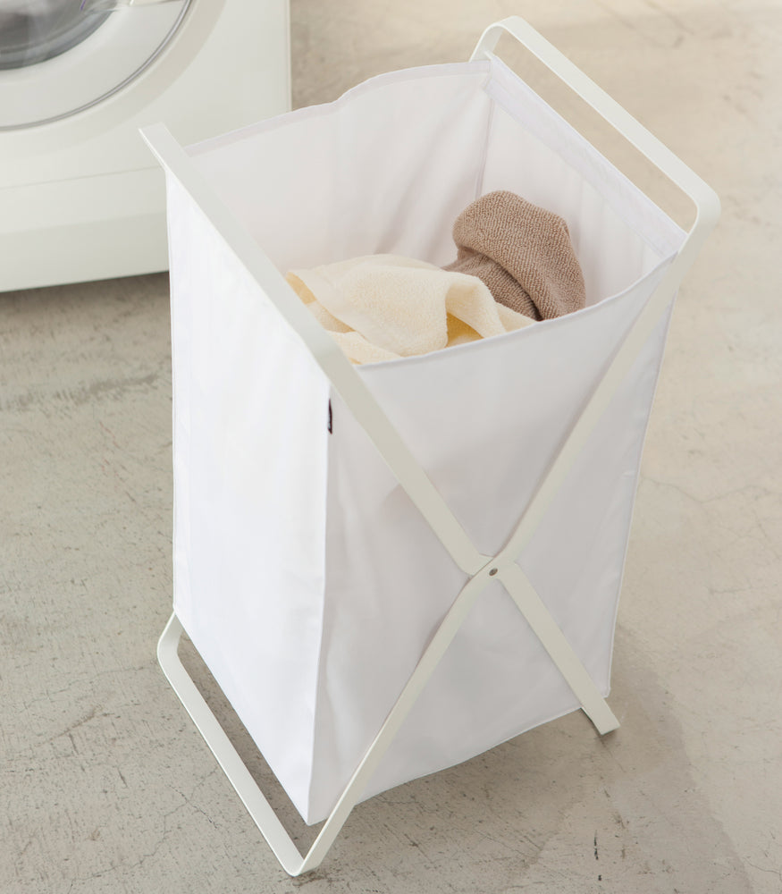 View 3 - White Laundry Hamper Storage Organizer containing towels in laundry room by Yamazaki Home.