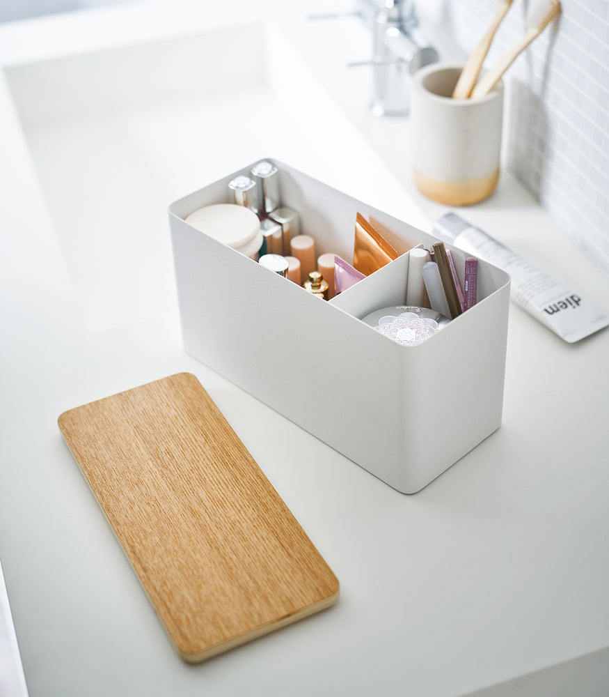 View 6 - White Countertop Organizer holding makeup products with cover off on bathroom countertop by Yamazaki Home.
