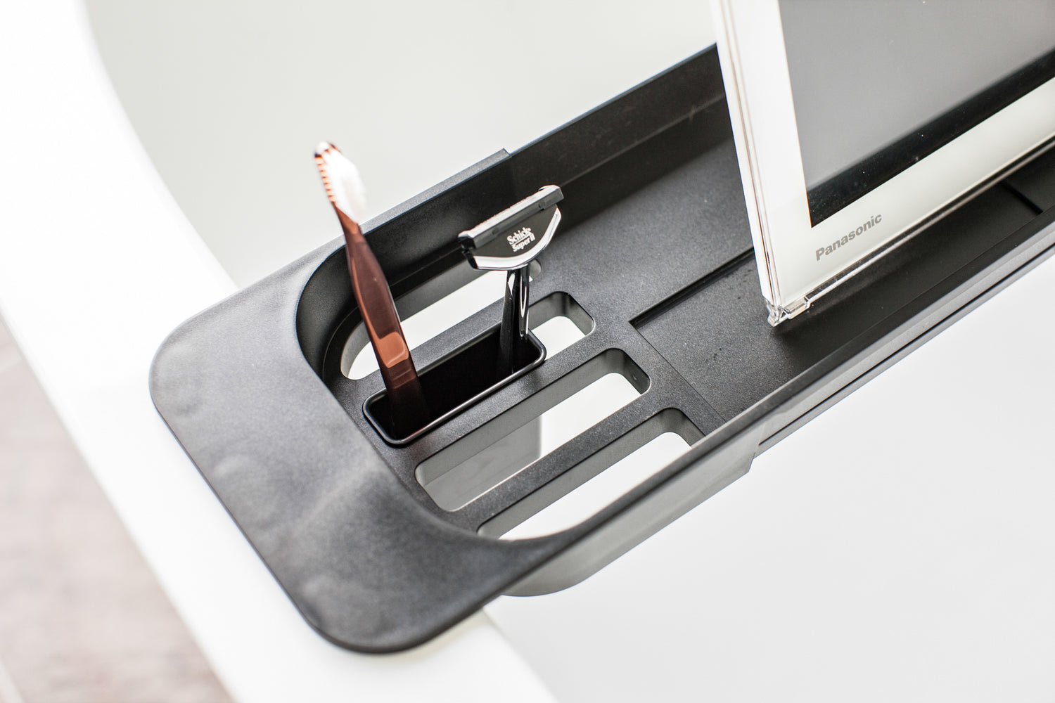 View 11 - Close up aerial view of black Expandable Bathtub Caddy holding razor and toothbrush by Yamazaki Home.