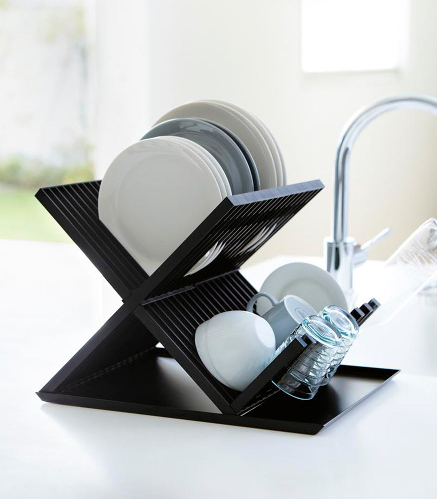 View 9 - Side view of black X-Shaped Dish Rack holding plates and cups on countertop by Yamazaki Home.