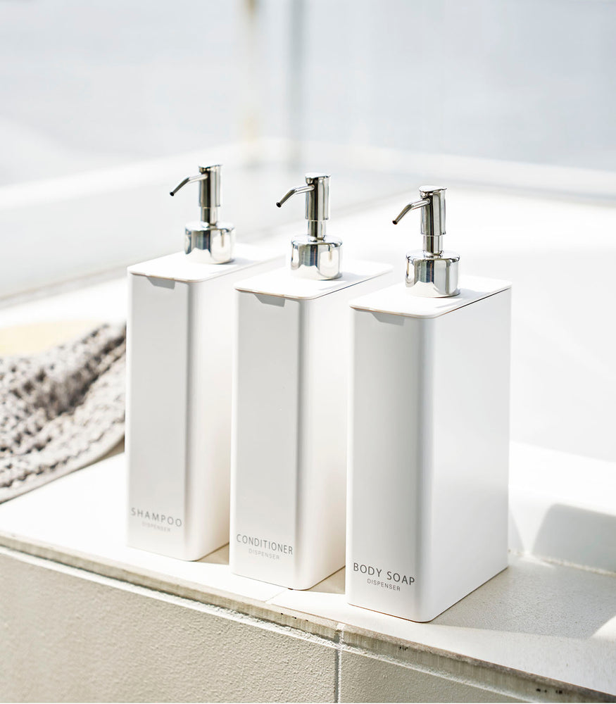 View 2 - Yamazaki Home white Shampoo, Conditioner, and Body Soap dispensers next to the bathtub.