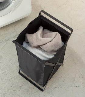 Aerial view of black Laundry Hamper Storage Organizer holding towels in laundry room by Yamazaki Home. view 9