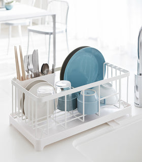 Front view of white Dish Rack holding dinnerware positioned next to kitchen sink by Yamazaki Home. view 8