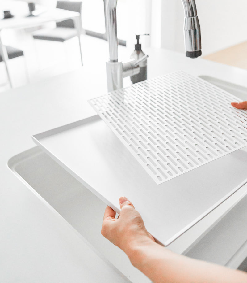 White Dish Drainer Tray with removable top in kitchen sink by Yamazaki Home.