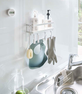 White Magnetic Organizer with Easy-Grip Rotating Clips holding cleaning items above sink by Yamazaki Home. view 4