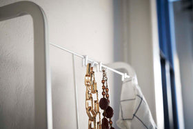 Close up top view of white Leaning Ladder with Grid Panel hooks holding necklaces  by Yamazaki Home. view 5