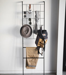 Front view of black Leaning Ladder with Grid Panel holding clothing and accessories by Yamazaki Home. view 9