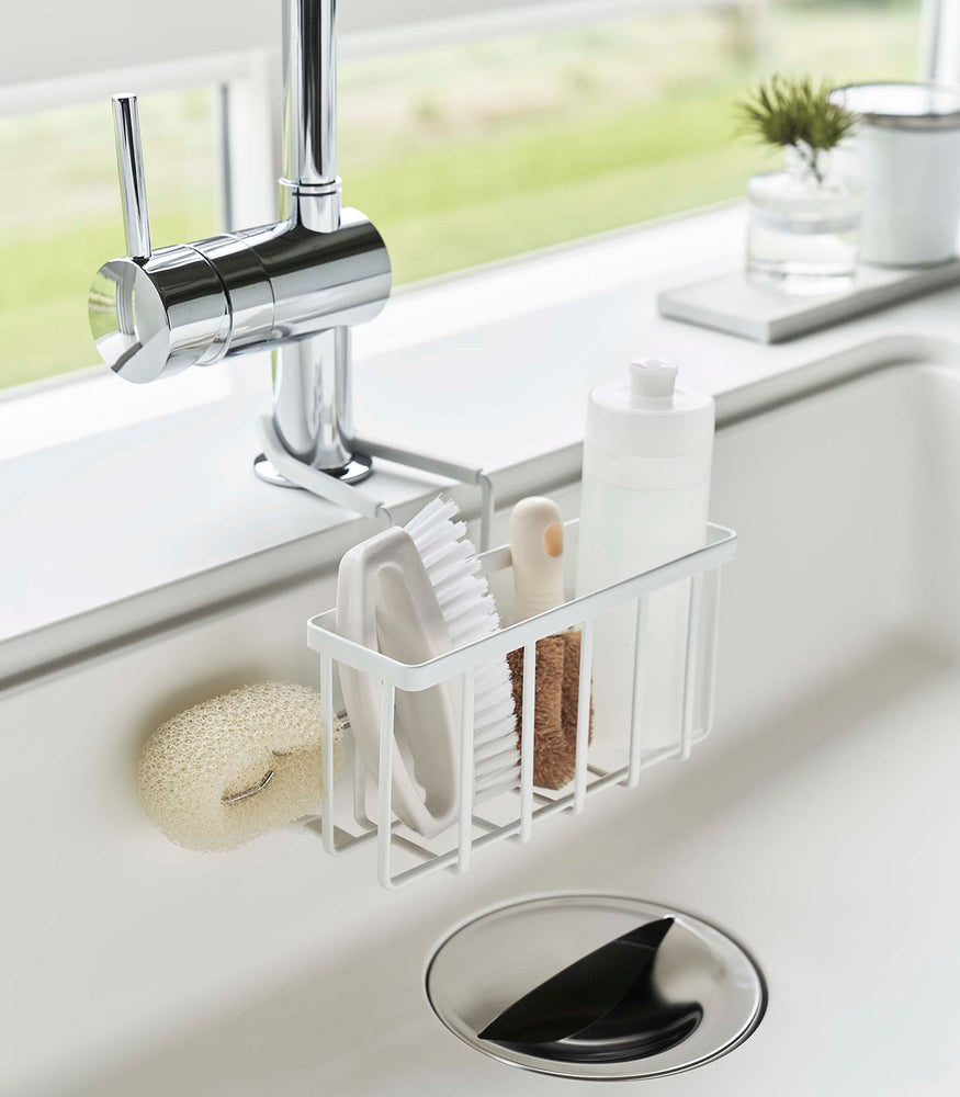 View 2 - Yamazaki Home white Faucet-Hanging Sponge Caddy attached to a kitchen sink