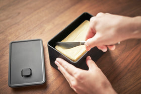 Aerial view of person using knife to get butter out of black Vacuum-Sealing Butter Dish by Yamazaki Home. view 11