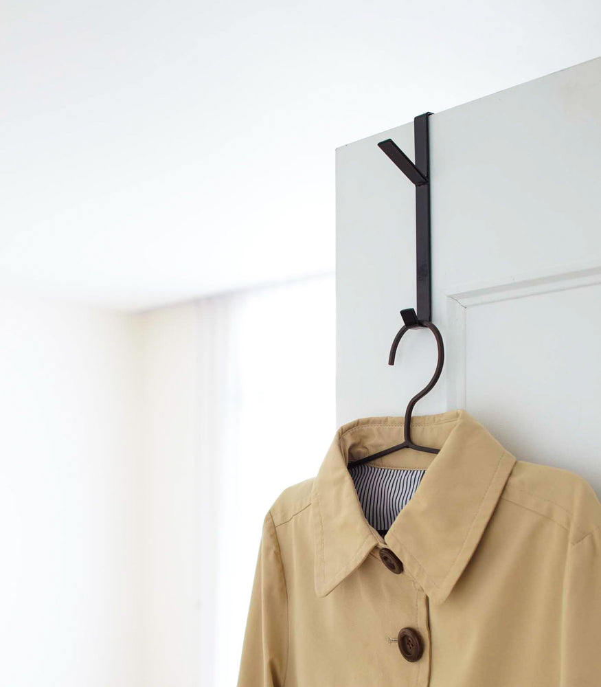 View 5 - Black Over-the-Door Hanger displaying jacket on closet door by Yamazaki Home.