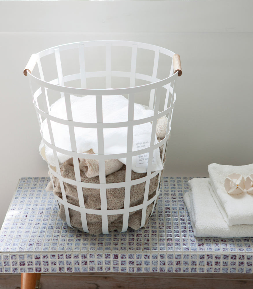 View 5 - Front view of white Round Laundry Basket holding towels in laundry room by Yamazaki Home.