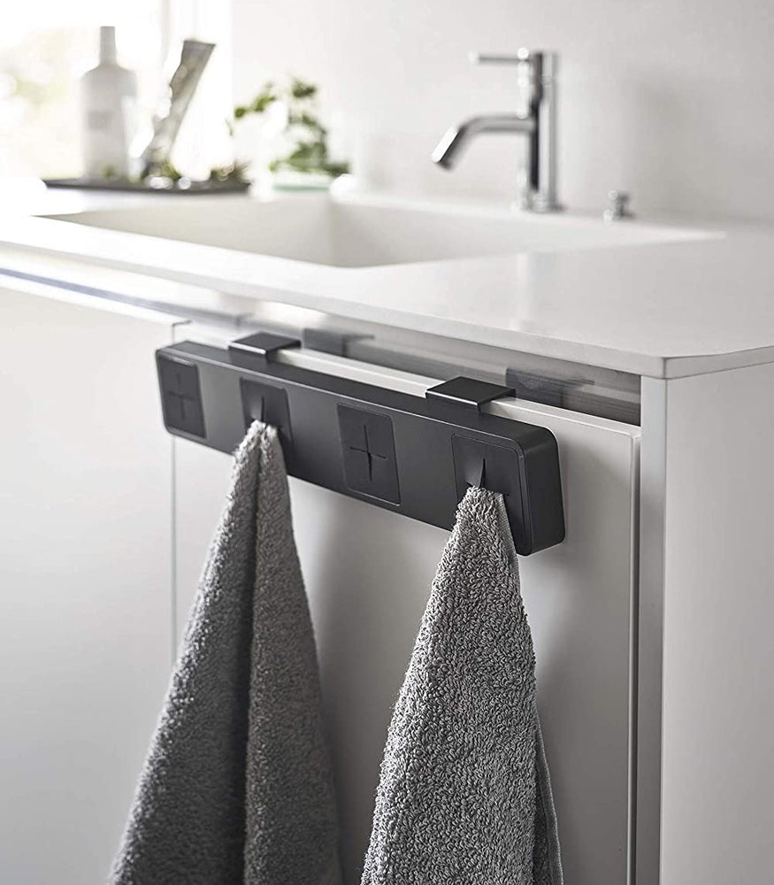 View 11 - Black Push Dish Towel Holder holding towels in bathroom by Yamazaki Home.