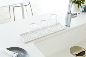 White Sink Drainer Tray with glasses on sink counter by Yamazaki Home. view 2