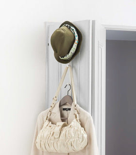 White Over-the-Door Hanger displaying hat, purse, and jacket on door by Yamazaki Home. view 4