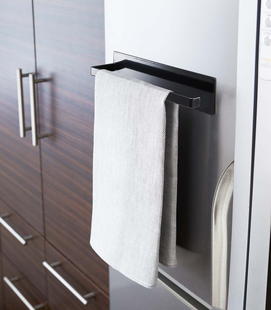View 10 - Black Magnetic Paper Towel Holder holding dish towel in kitchen by Yamazaki Home.