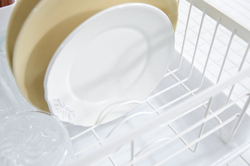 Close up view of White Dish Rack holding plates and cups by Yamazaki Home.