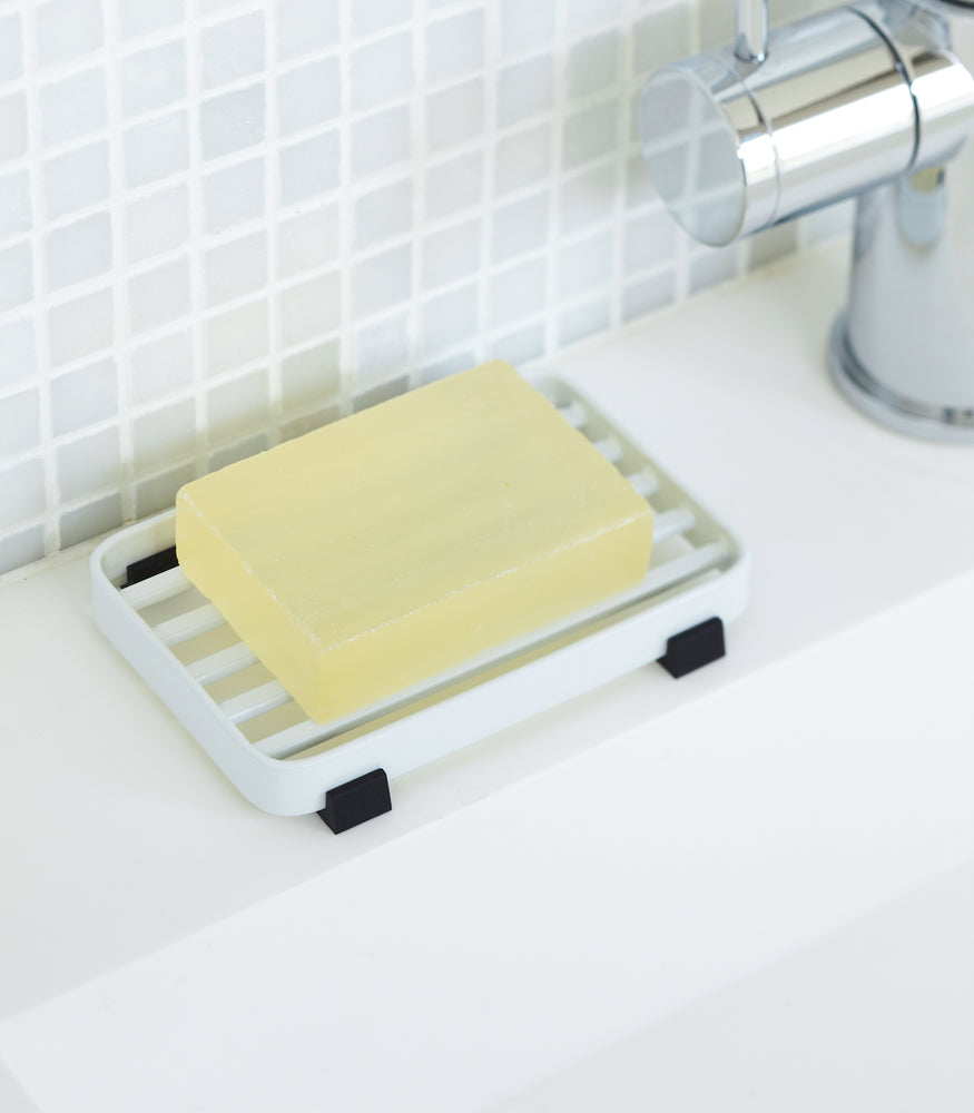 View 3 - White Slotted Soap Tray on sink counter holding soap by Yamazaki Home.