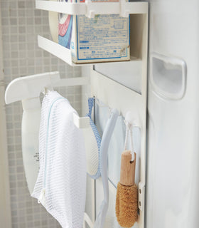 Close up side view of white Magnet Laundry Storage Pockets holding cleaning items by Yamazaki Home. view 5