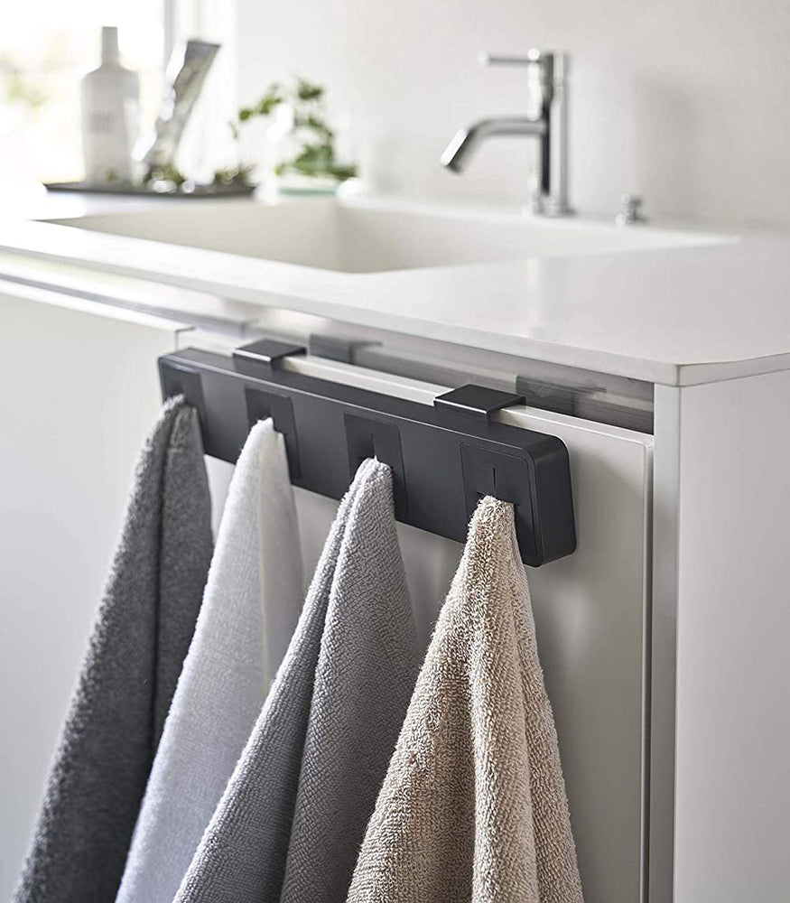 View 12 - Black Push Dish Towel Holder holding towels in bathroom by Yamazaki Home.