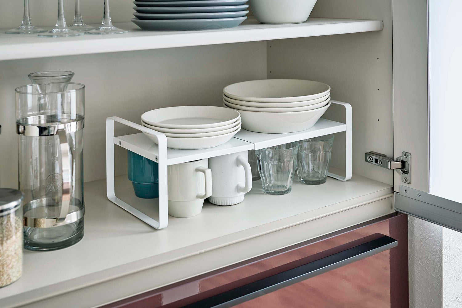 View 5 - White Expandable Countertop Organizer expanded holding plates in kitchen cabinet by Yamazaki Home.