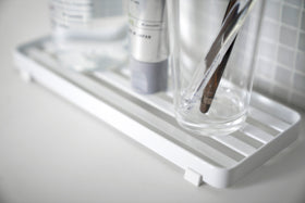 Close up view of white Slotted Tray holding sink accessories in bathroom by Yamazaki Home. view 4