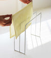 Close up view of white Dish Towel Holder holding towel on white countertop by Yamazaki Home.
