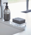 Self Draining Soap Tray on holding sponge on sink counter by Yamazaki Home.