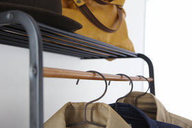 Close up top view of black Leaning Coat Rack with Shelf holding bag, hat, and clothes by Yamazaki Home. view 8