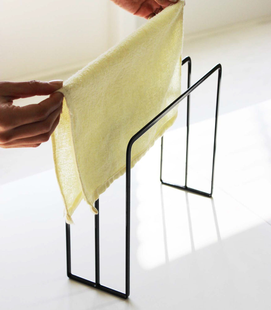 View 8 - Close up view of black Dish Towel Holder holding towel on white countertop by Yamazaki Home.