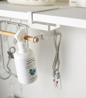 Close up of white Undershelf Hanger holding cleaning supplies by Yamazaki Home. view 6